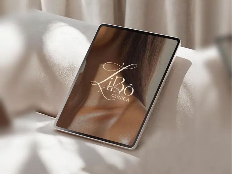 Tablet apoiado em um sofá claro exibindo o logotipo da Clínica LiBô