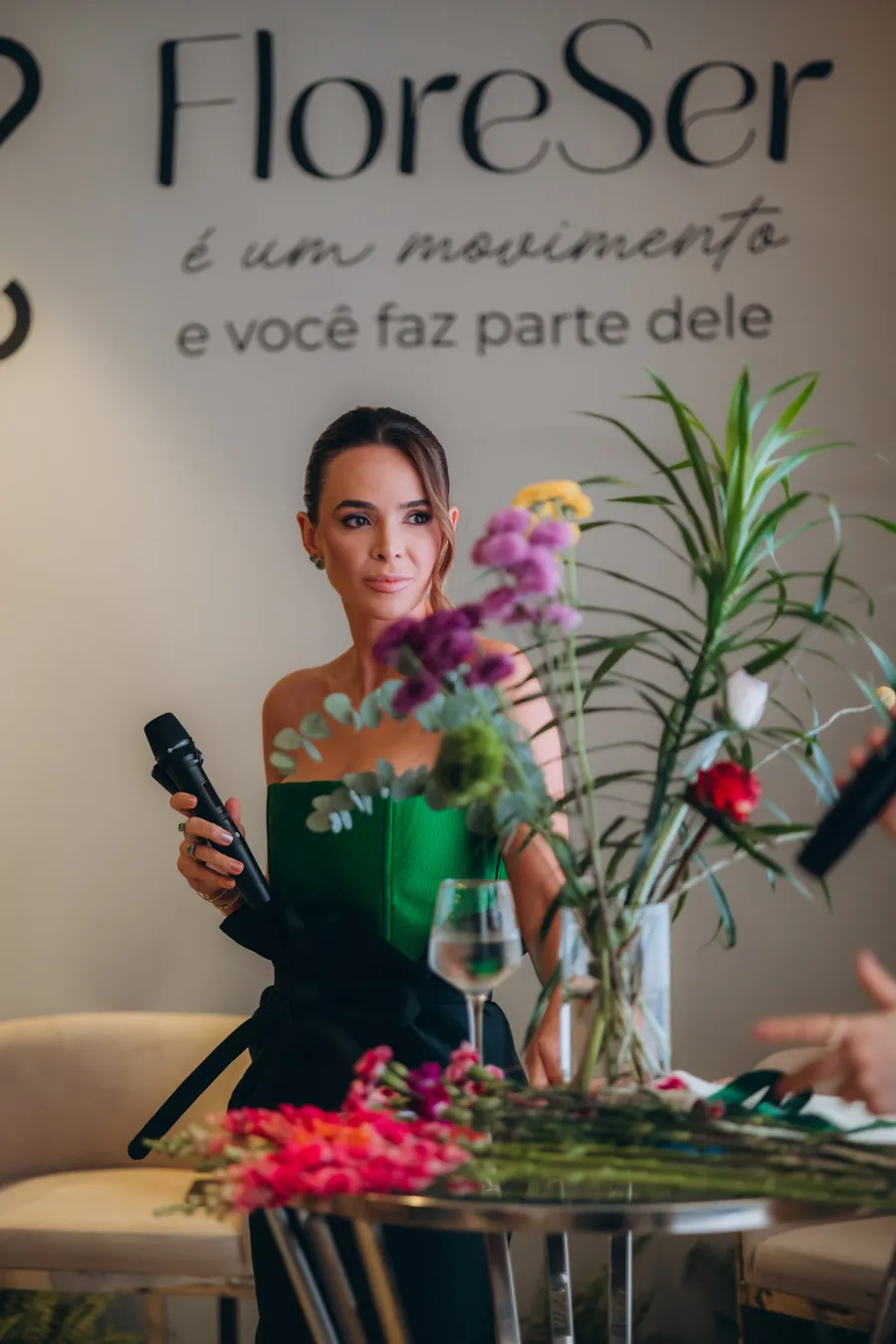 Médica com microfone em mesa florida, durante encontro do Clube FloreSer