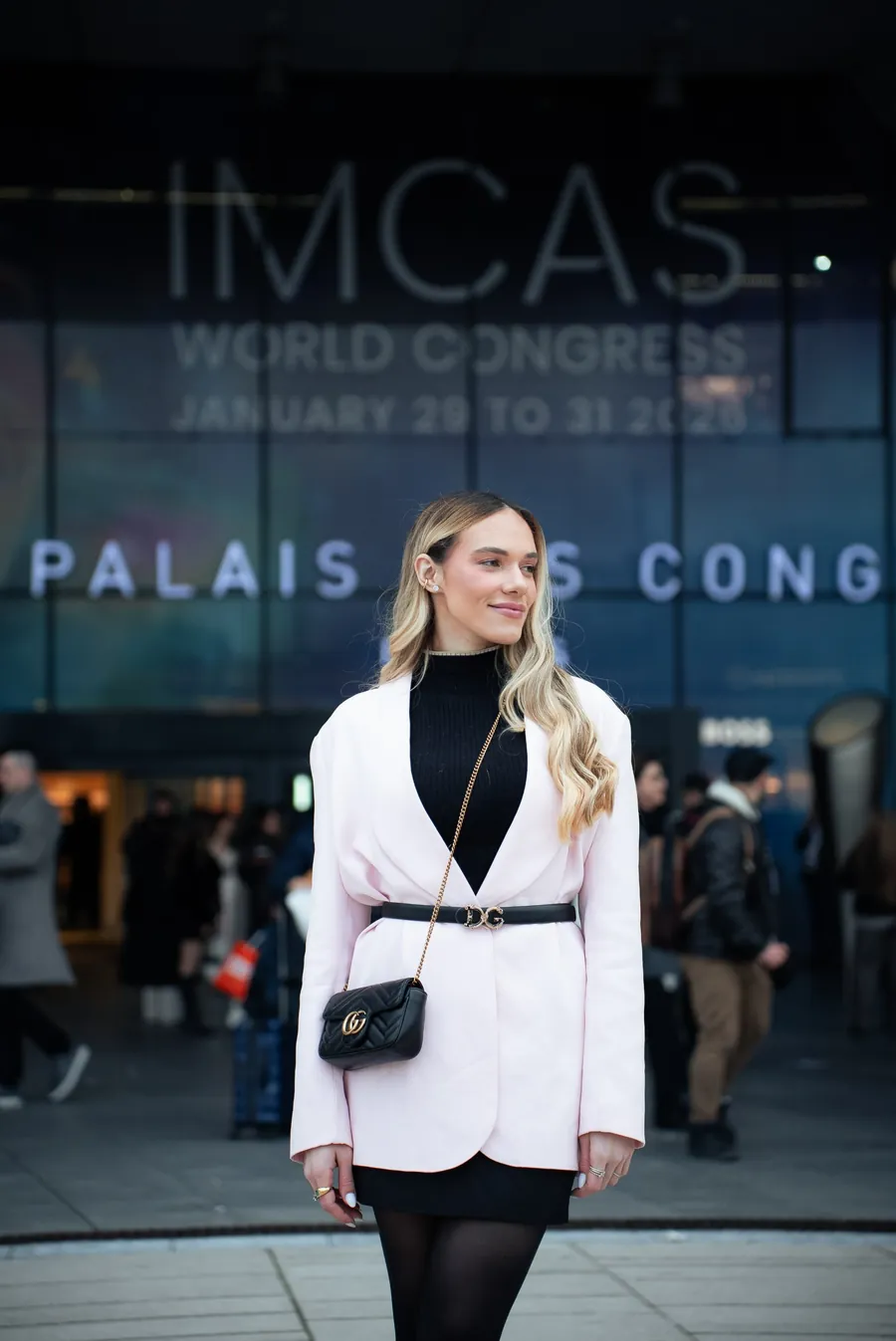 Participante em frente à fachada do IMCAS World Congress, no Palais des Congrès, em Paris
