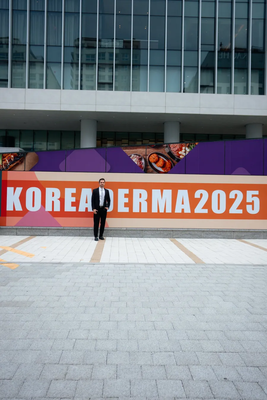 Participante em frente ao painel do KoreaDerma 2025, na Coreia do Sul